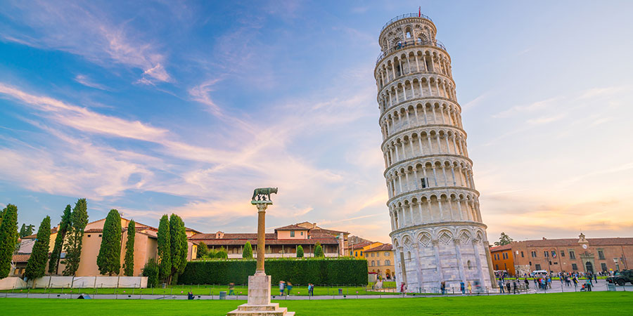 The iconic Leaning Tower of Pisa stands in front of a clear blue sky.